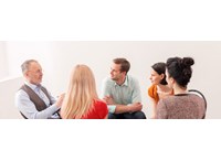 A psychologist leads a group of people in a group therapy session