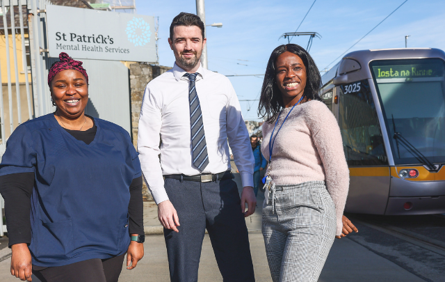 Three members of the nursing team at St Patrick's Mental Health Services stand outside the entrance to St Patrick's University Hospital in Dublin, with the LUAS seen in the background.