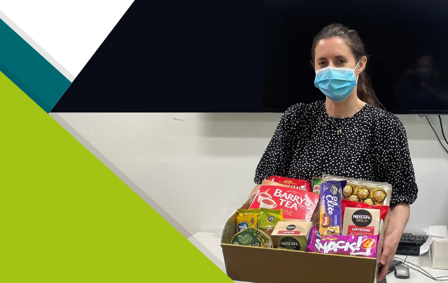Photo of a member of nursing staff from St Patrick's Mental Health Services receiving a hamper filled with edible gifts after winning a prize through the Staff Wellbeing Committee.