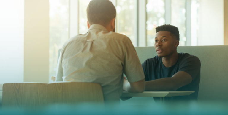 Two people talk together while sitting at a table during a social visit.