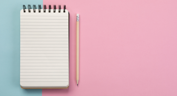 Photo of an open lined notebook and a pencil, set against a blue and pink background