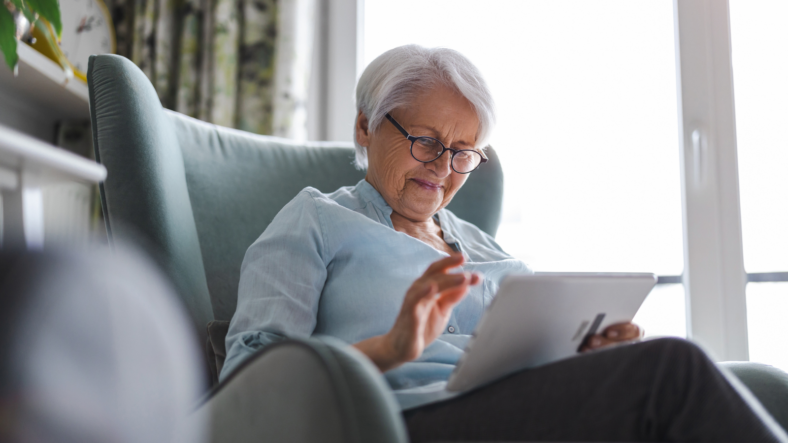 This is an image of a female senior citizen at home browsing on a tablet.